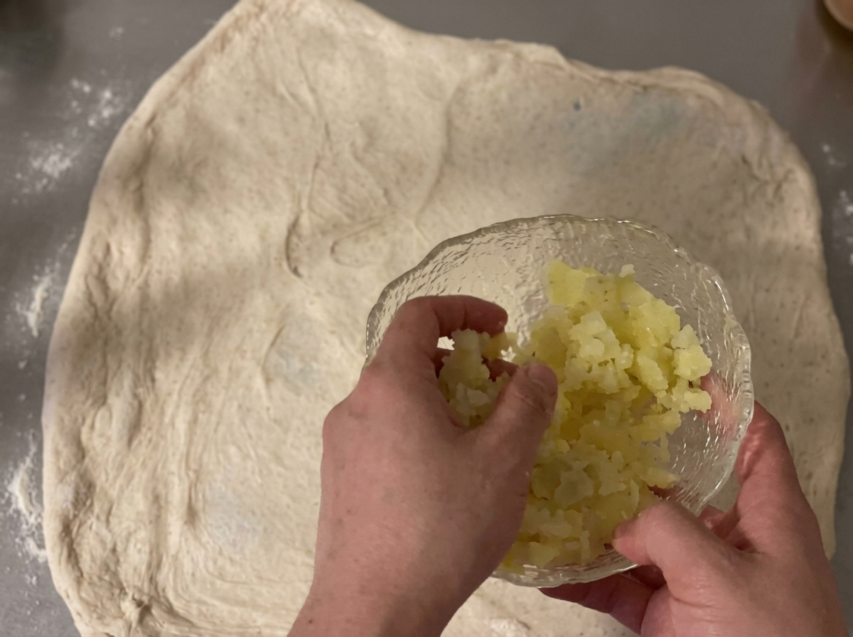 Dés de pommes de terre et cheddar râpé dispersés sur une abaisse de pâte.