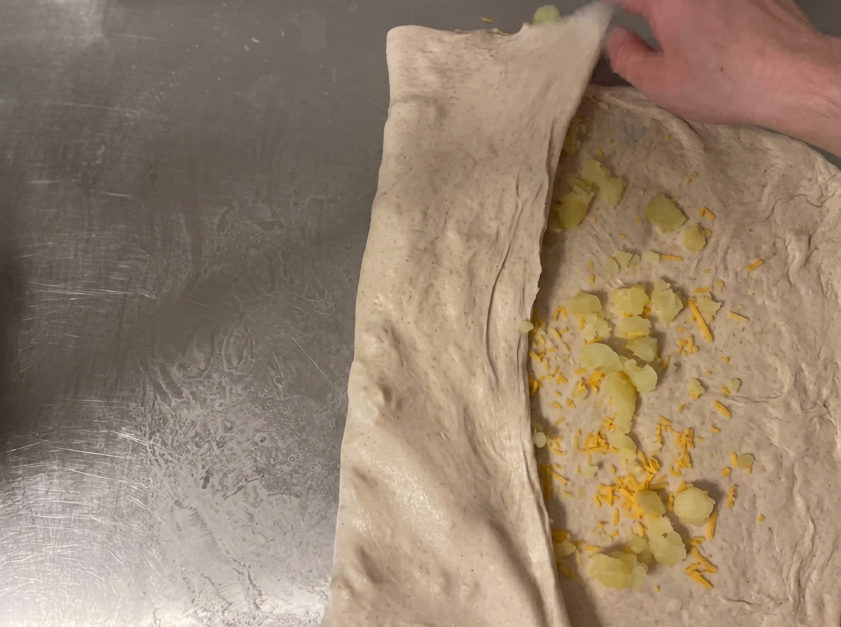 Pâte roulée sur le comptoir pour enfermer le fromage et les pommes de terre.