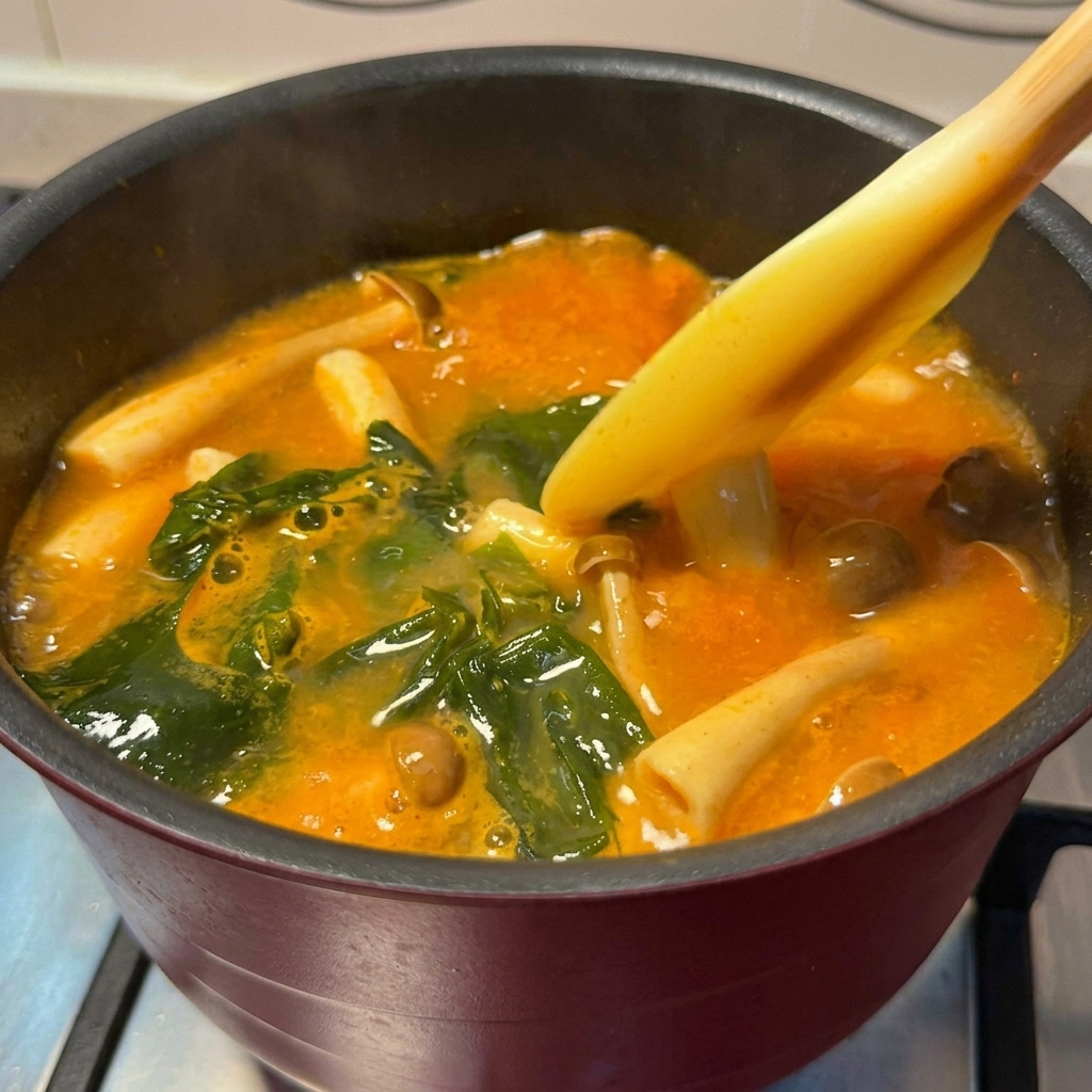 Morceaux de saumon dorés ajoutés dans une marmite de soupe miso épicée mijotante.