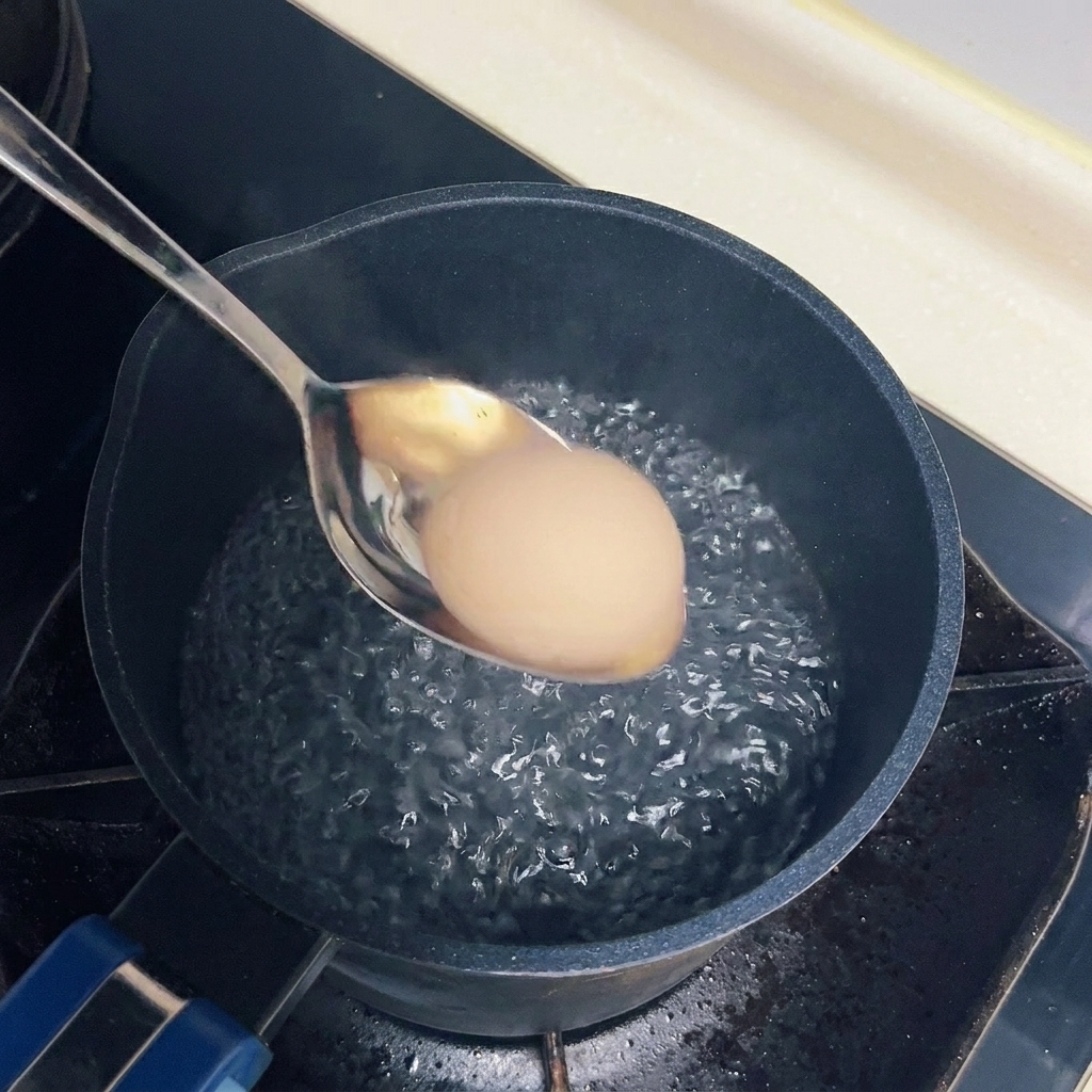 Un œuf plongé délicatement dans une casserole deau frémissante avec une cuillère en métal.