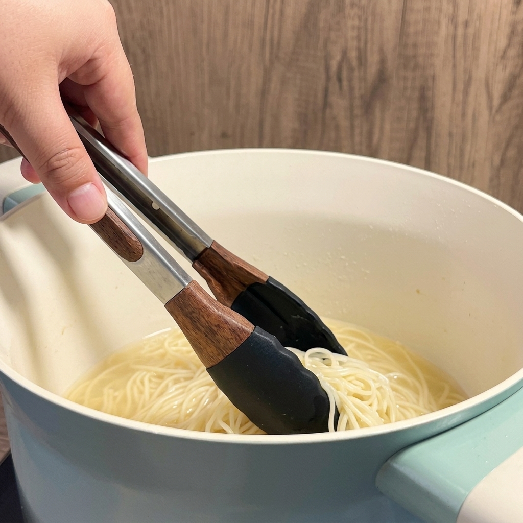 Nouilles ramen sèches plongées dans leau bouillante dans une casserole blanche.