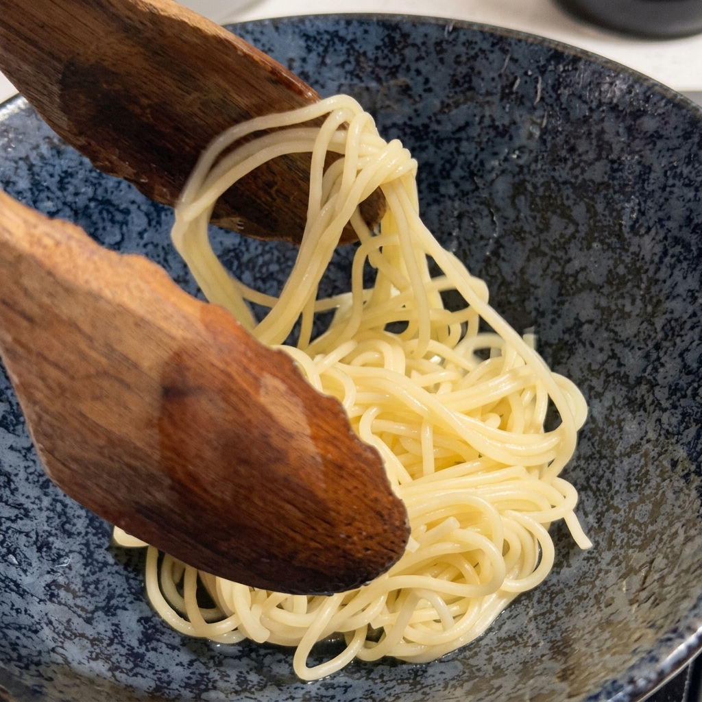 Nouilles ramen cuites retirées dune casserole avec une grande cuillère en bois.
