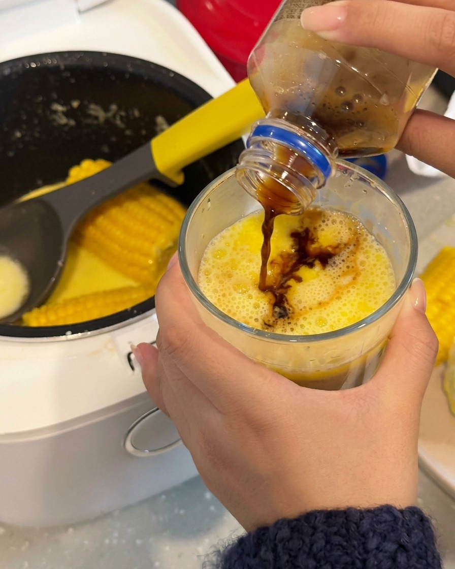 Café noir versé dans un verre contenant le bouillon de maïs laiteux et jaune.