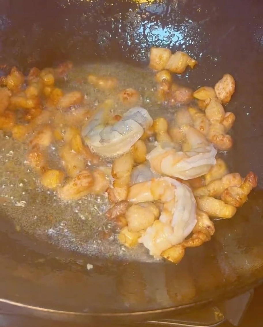 Crevettes, poitrine de porc et autres fruits de mer sautant ensemble dans un wok chaud.