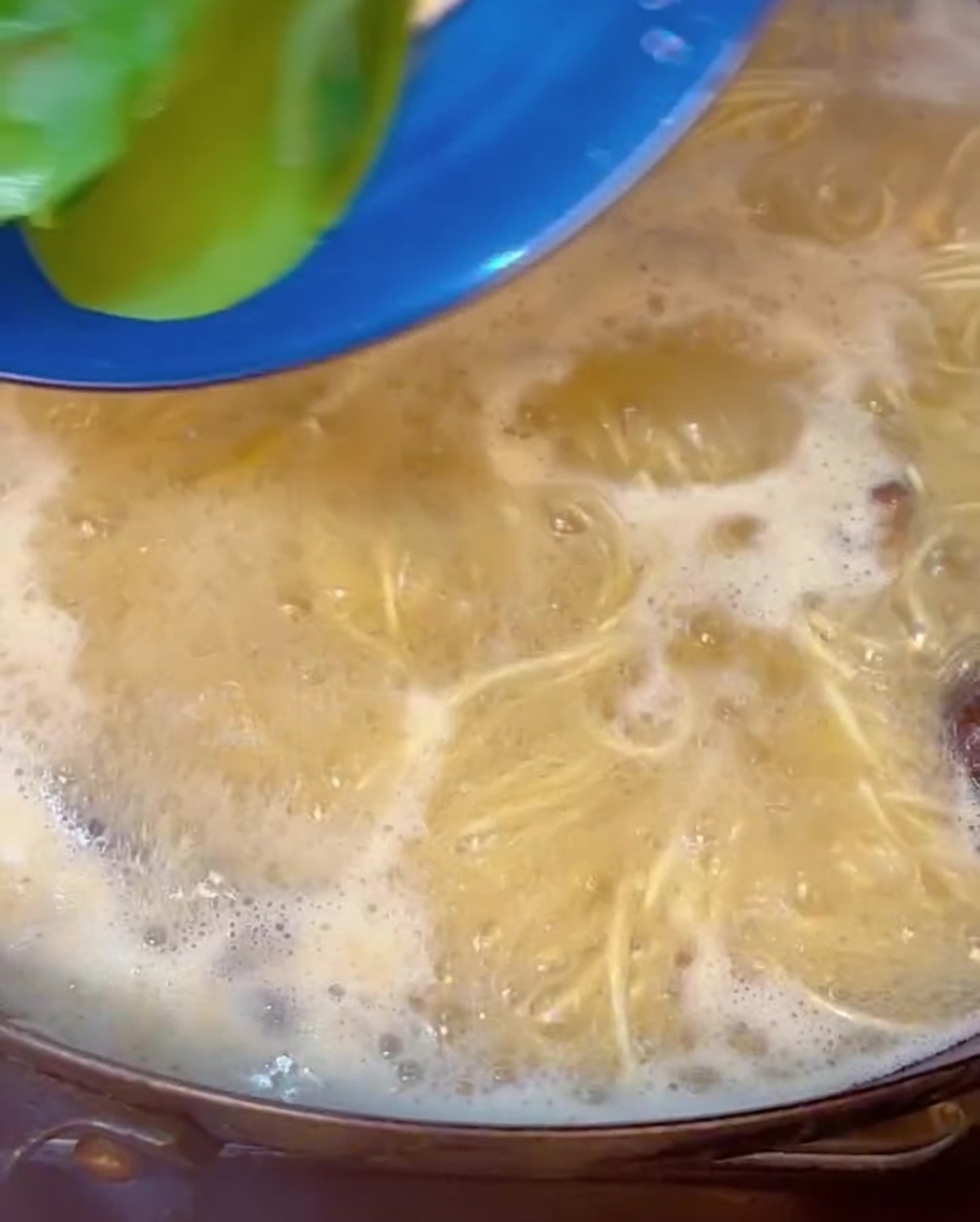 Du bok choy frais immergé dans une marmite de nouilles ramen et bouillon.