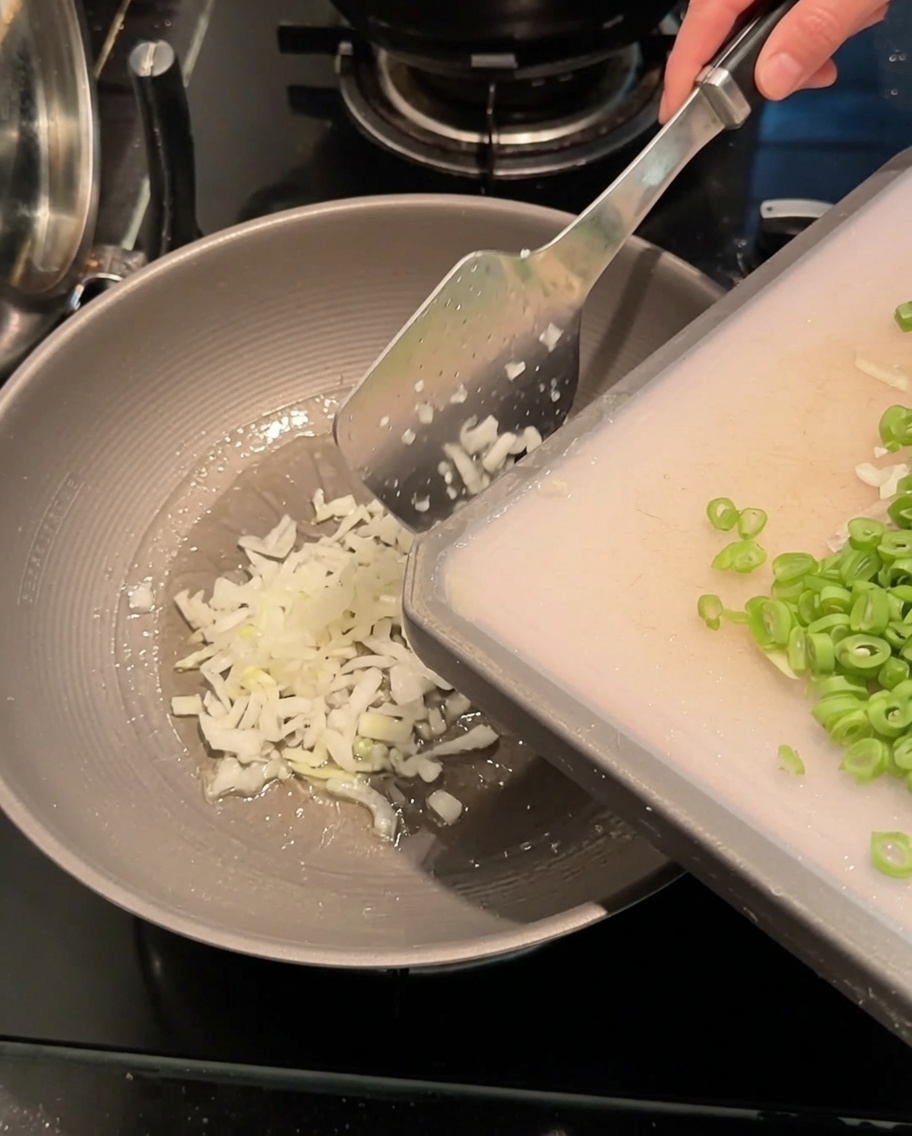 Oignons verts émincés et haricots longs coupés sautés dans un wok chaud avec de lhuile.