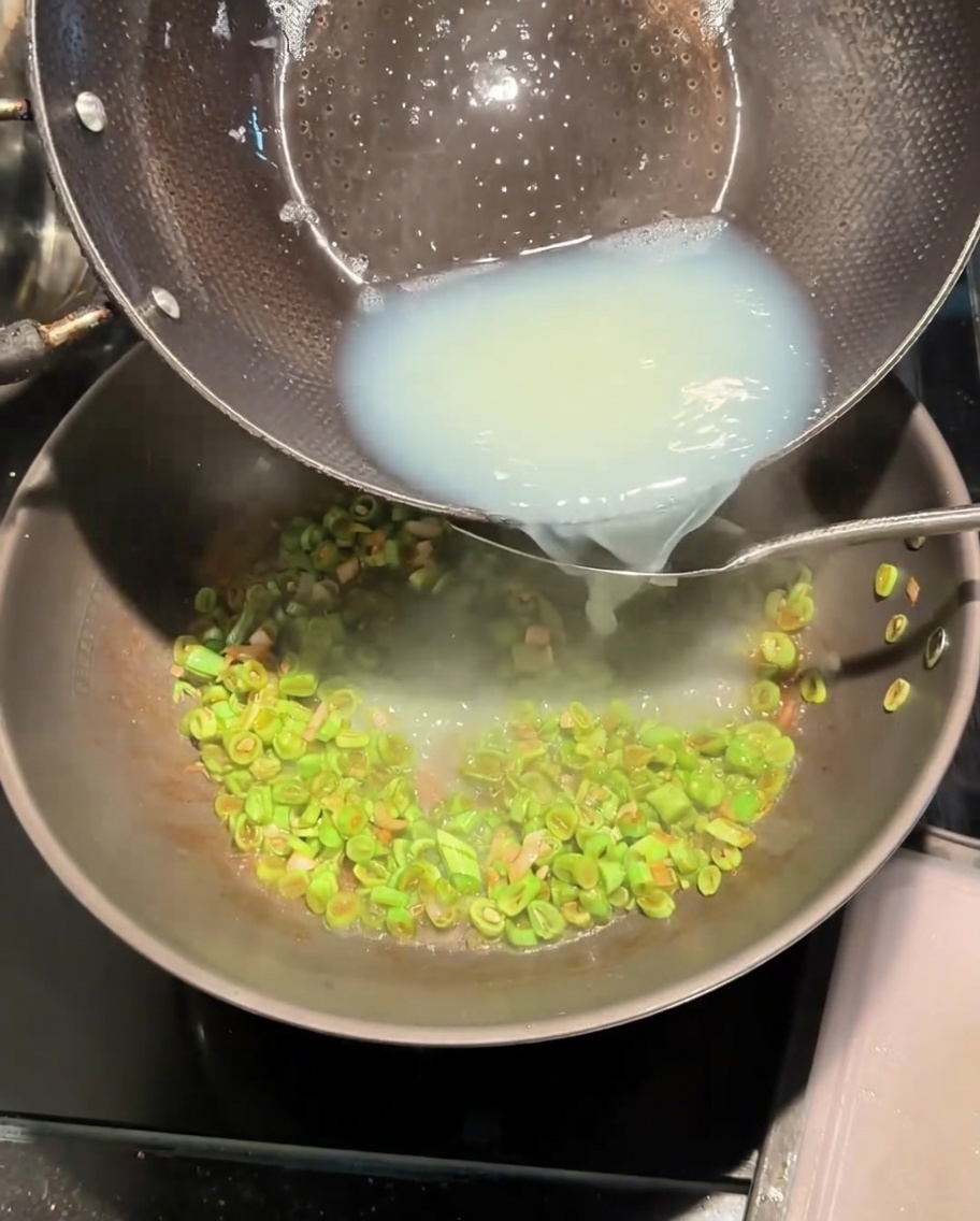 Verser le bouillon de palourdes blanc depuis une casserole dans le wok.