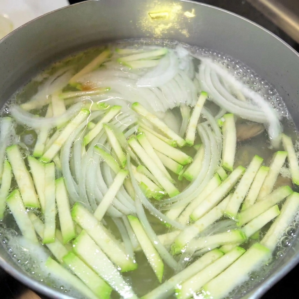 Gros plan sur lajout de sauce soja et de nuoc-mâm dans une marmite de bouillon.