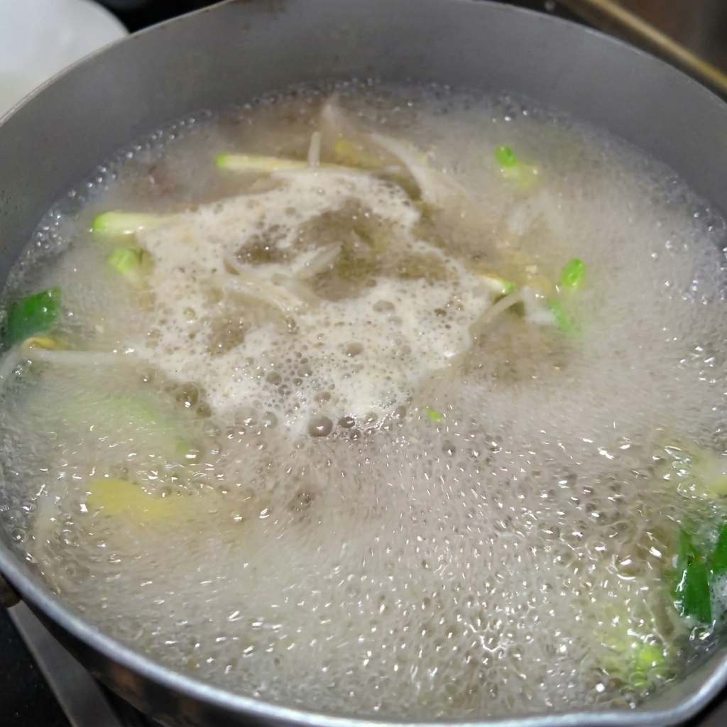 Nouilles étirées fraîches ajoutées dans la marmite de bouillon.