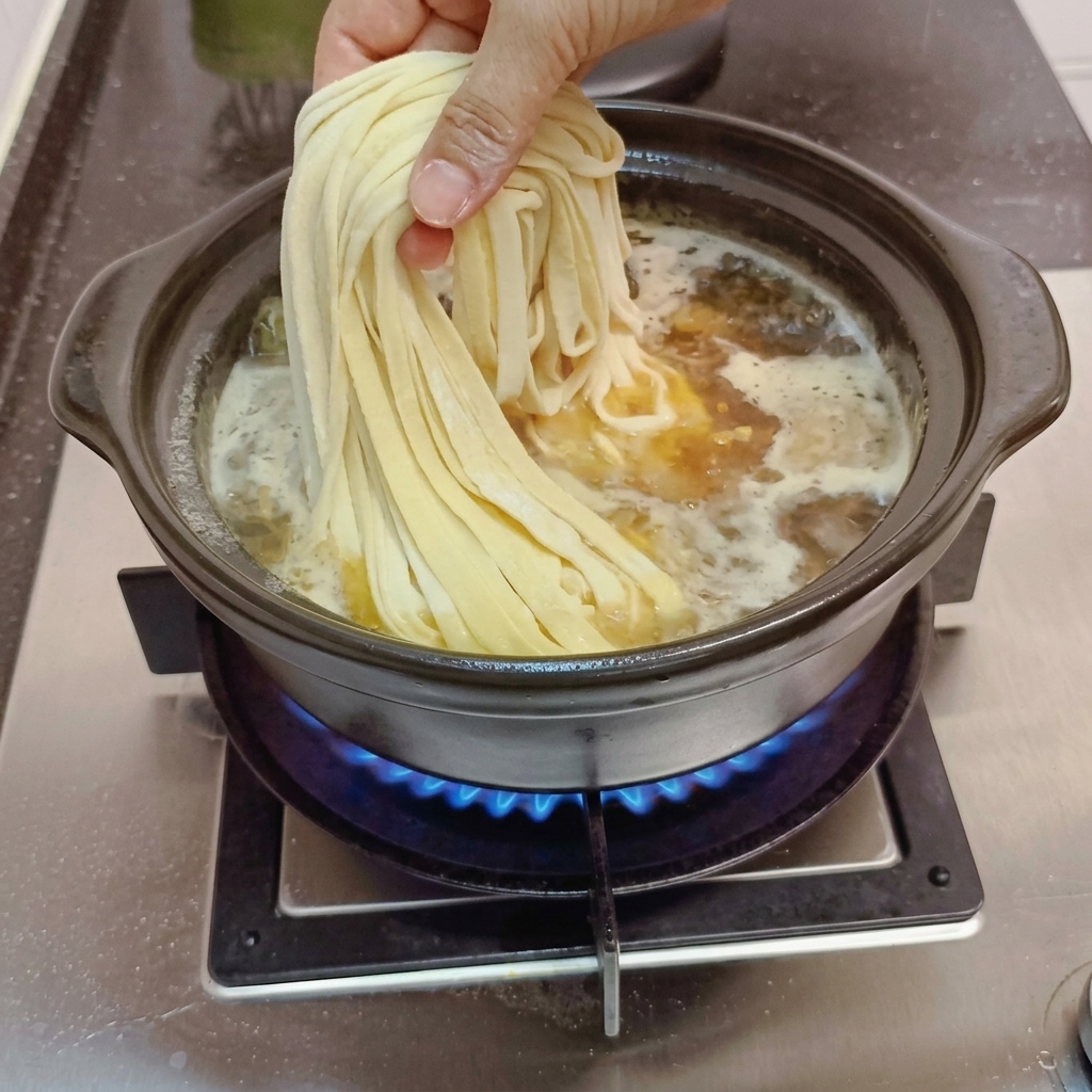 Nouilles faites maison ajoutées dans le bouillon frémissant.