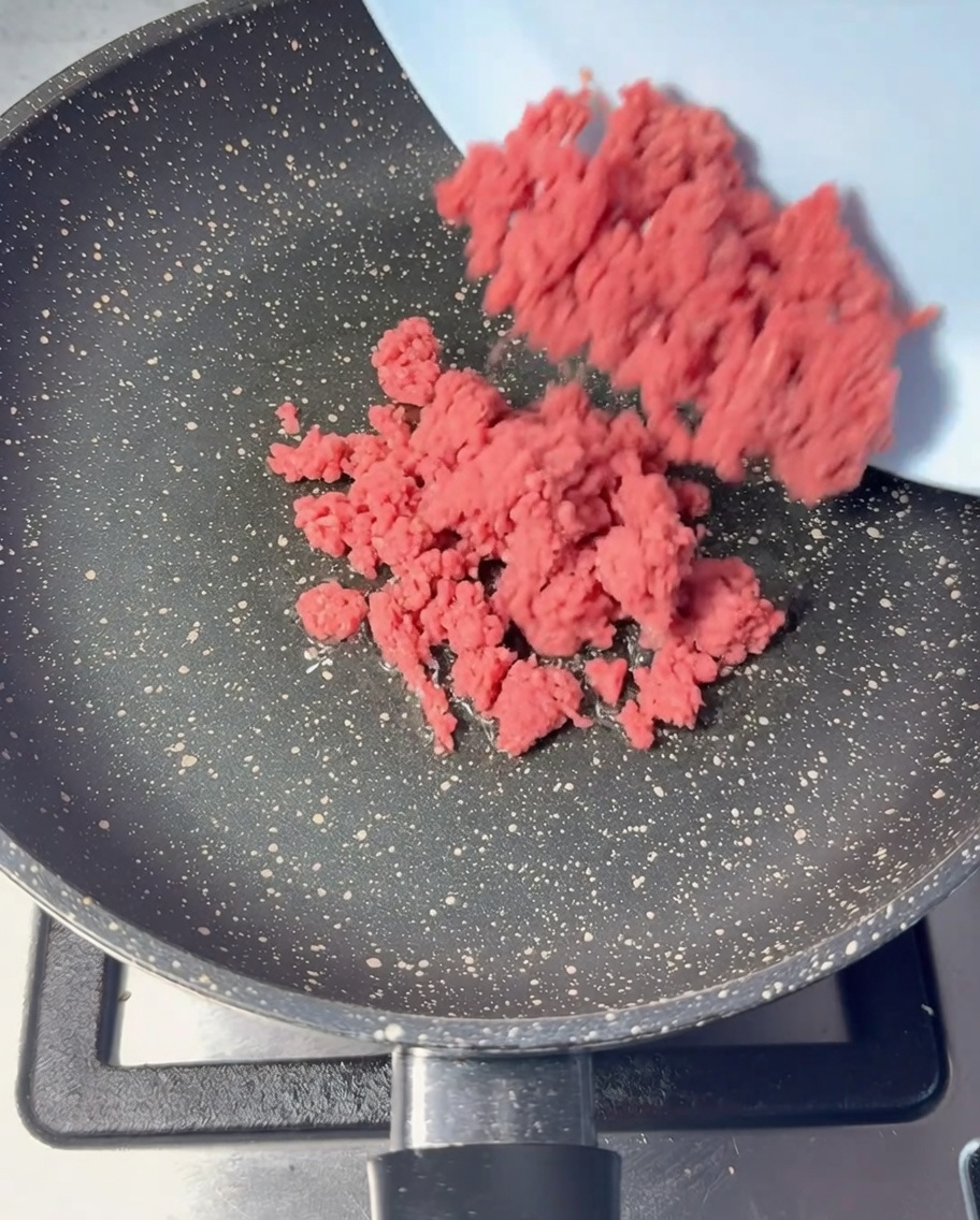 Du bœuf haché cru ajouté dans une poêle huilée.