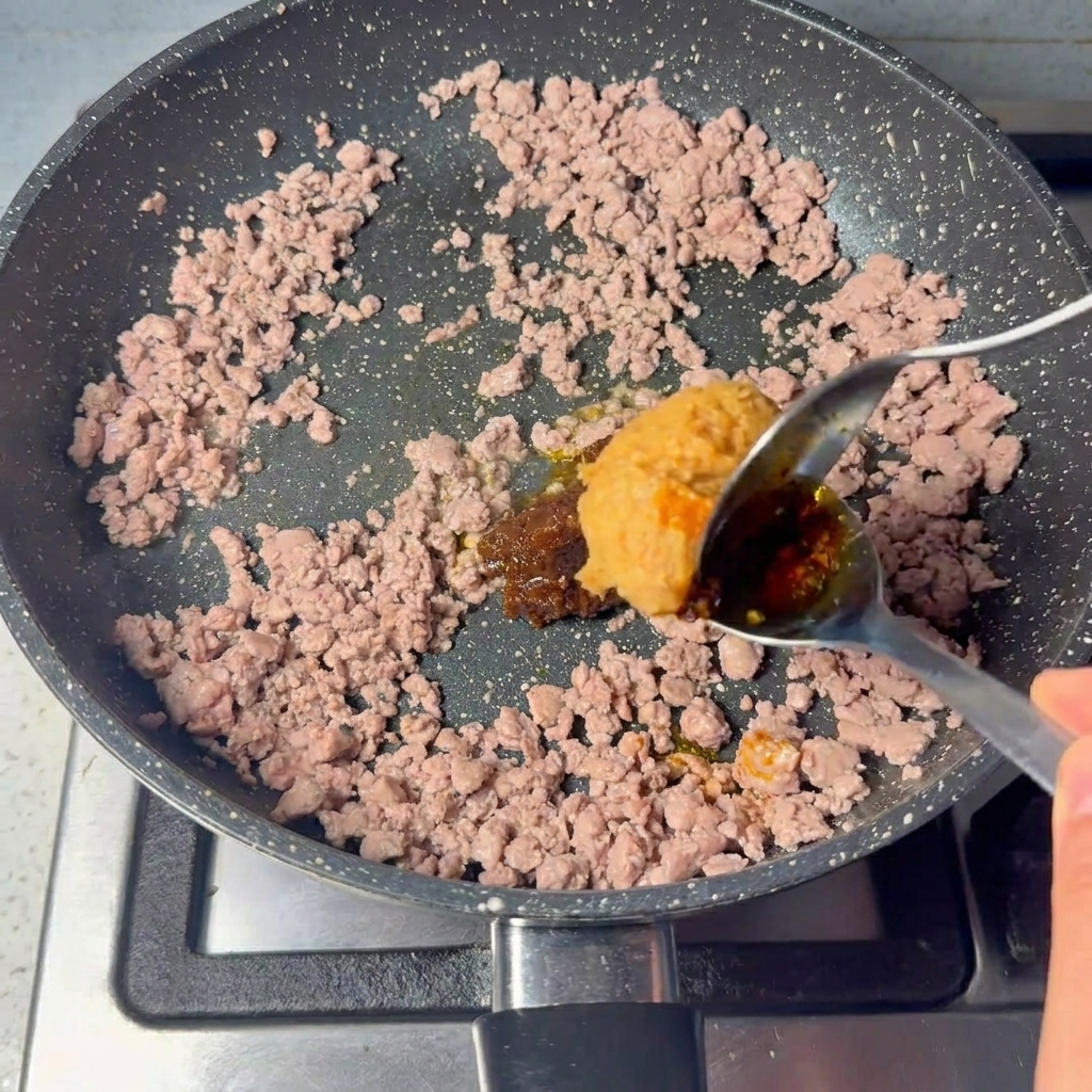 Une grosse cuillerée de pâte brune incorporée au bœuf cuit.