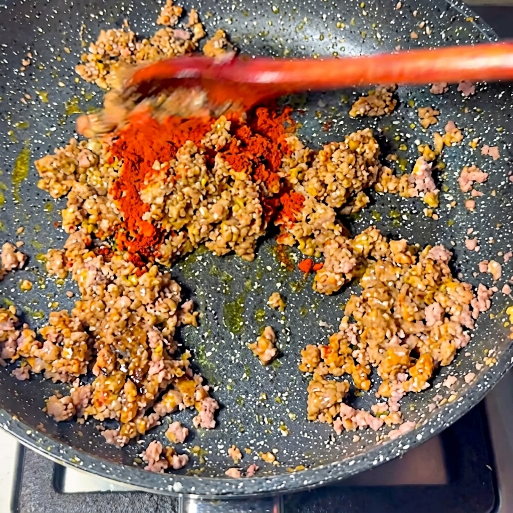 Poudre de chili rouge saupoudrée sur la viande.