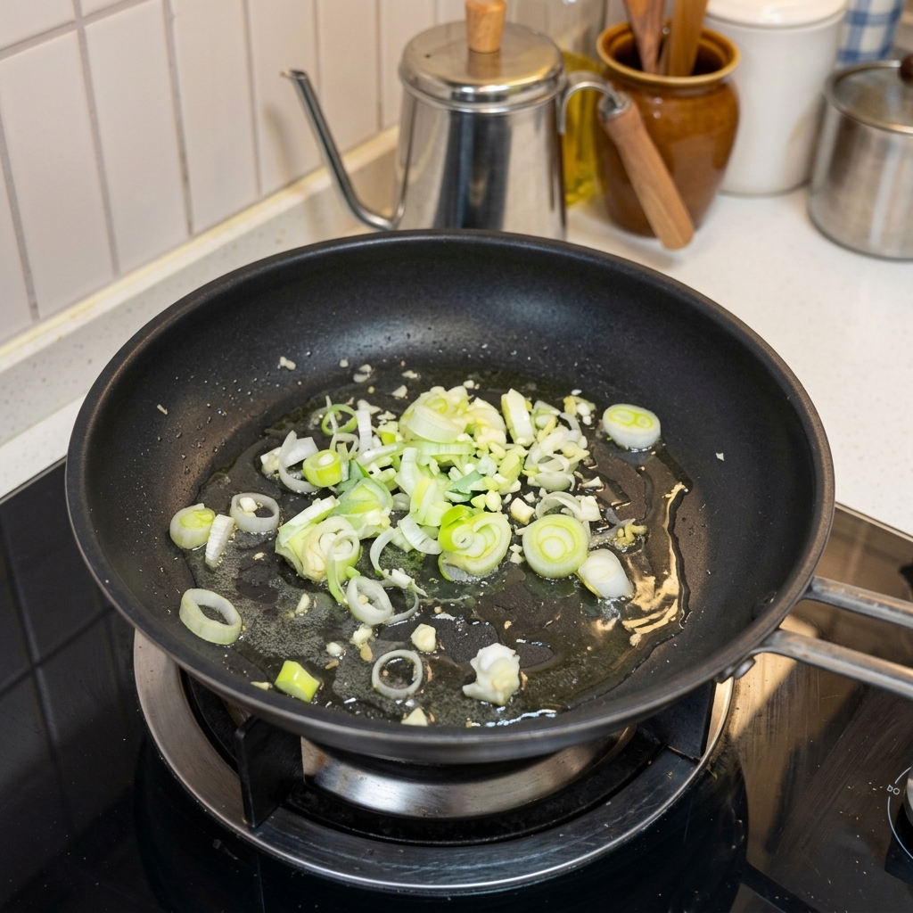 Ail haché et oignons verts sautant dans une poêle chaude avec de lhuile.