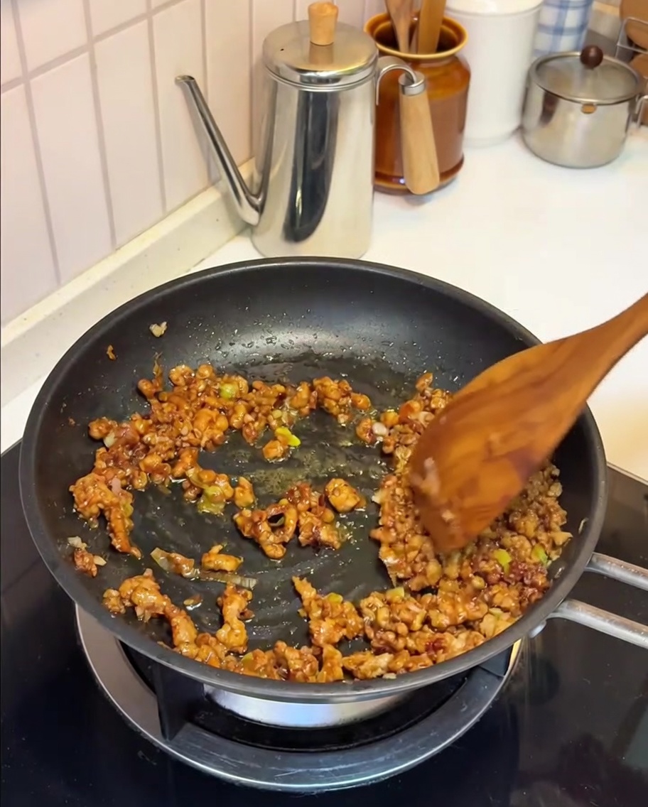 Lait de soja versé dans la poêle avec le mélange de porc et de miso.