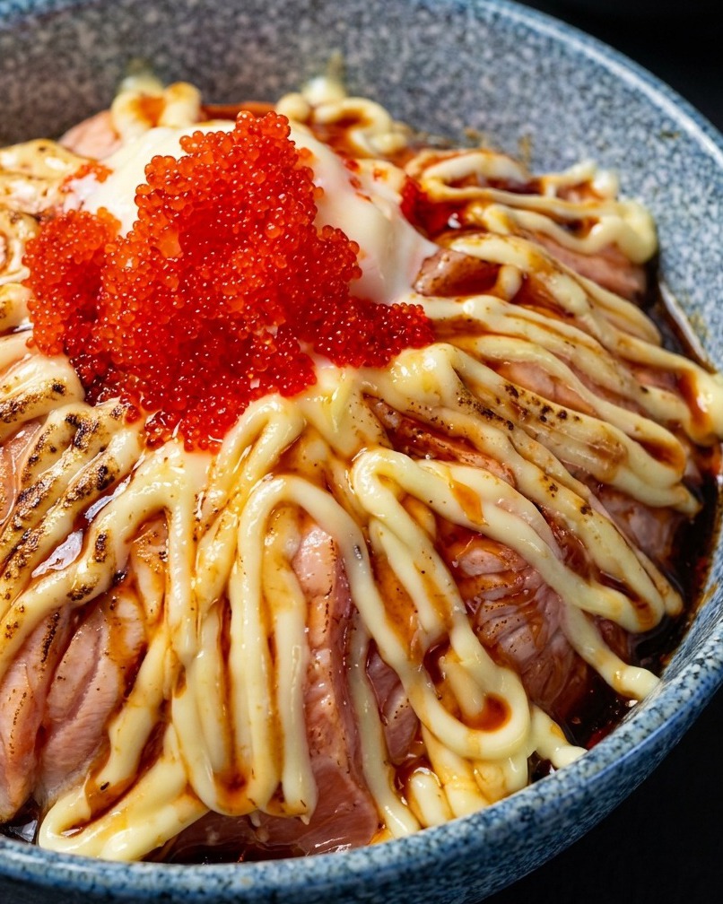 Le chalumeau saisissant légèrement le dessus dun bol de riz au saumon garni de mayonnaise et dœufs de poisson.