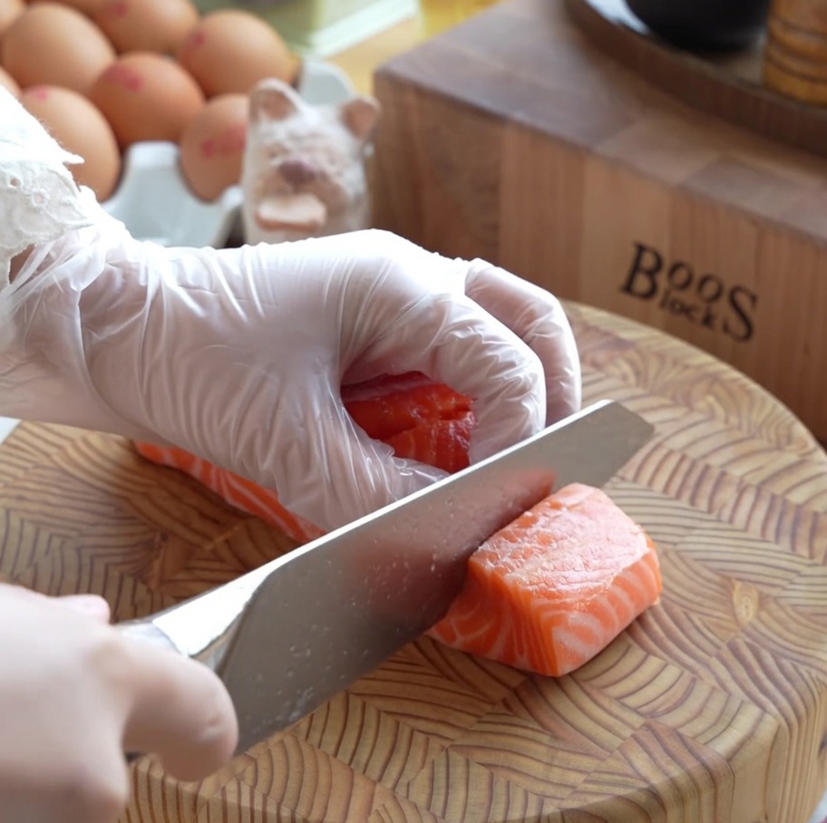 Dés de saumon frais cru soigneusement préparés sur une planche à découper en bois.