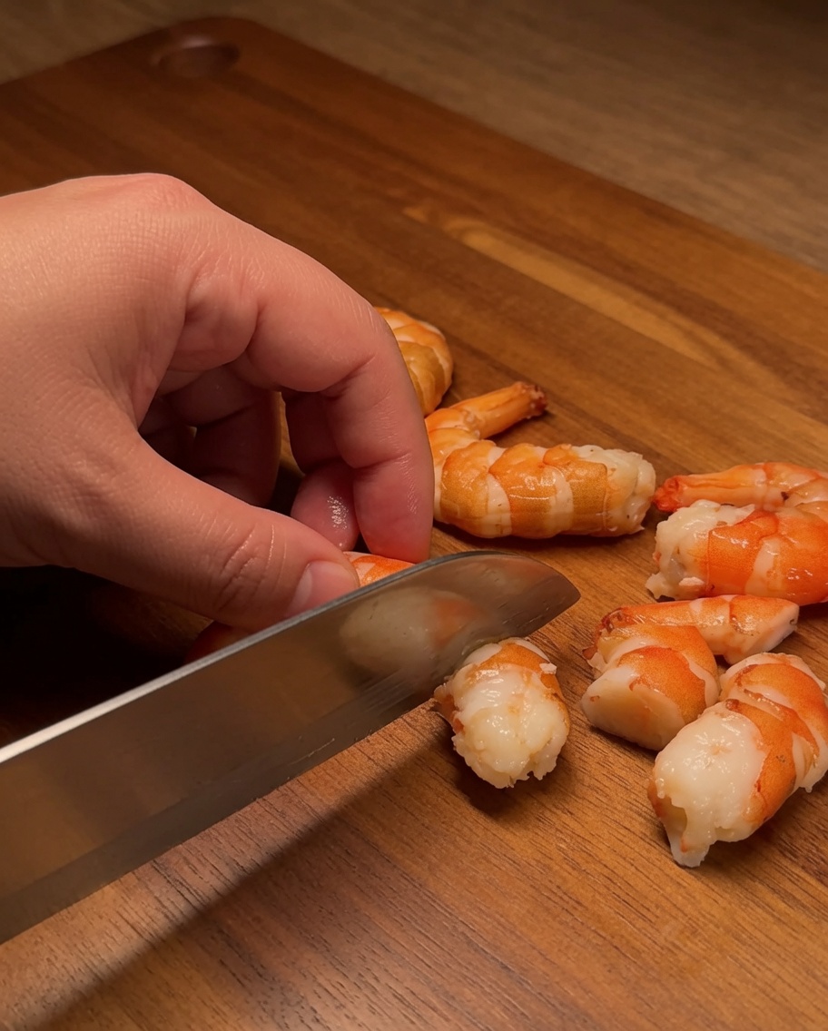 Un filet de saumon cru est coupé en cubes nets et uniformes sur une planche en bois.