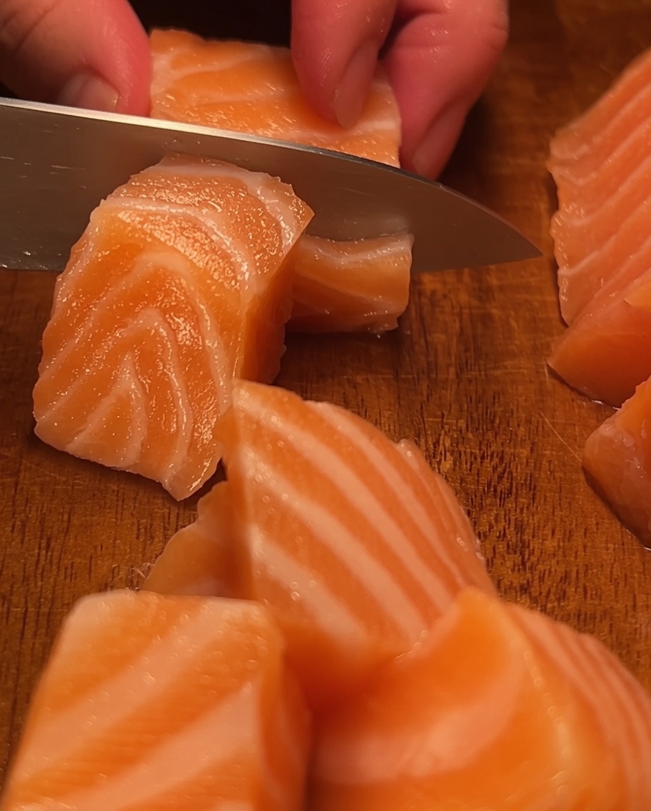 Un morceau danguille grillée est coupé en petits segments appétissants sur une planche à découper en bois.