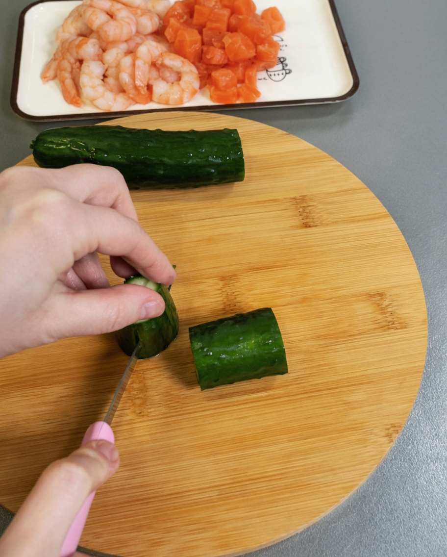 Concombre vert frais coupé en petits cubes sur une surface en bois.