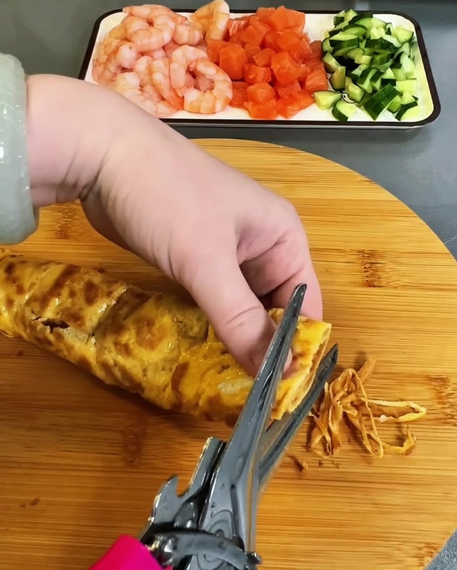 Omelette cuite coupée délicatement en fines lanières avec des ciseaux de cuisine.
