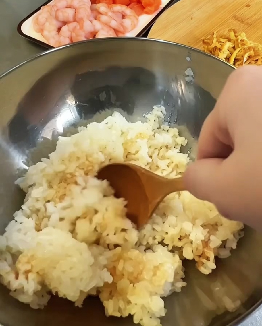 Riz cuit mélangé avec du vinaigre et de la sauce soja dans un bol en métal.