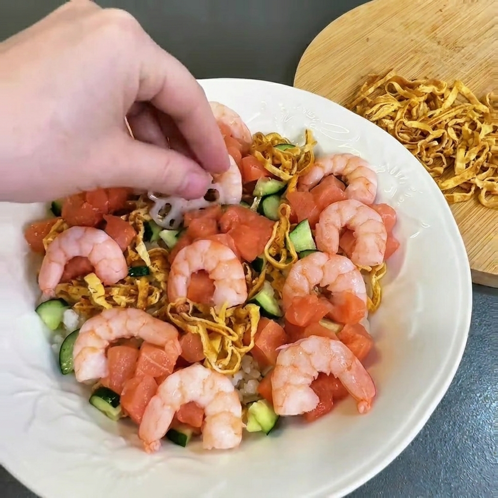 Crevettes roses cuites disposées soigneusement sur lassiette garnie de saumon et de concombre.