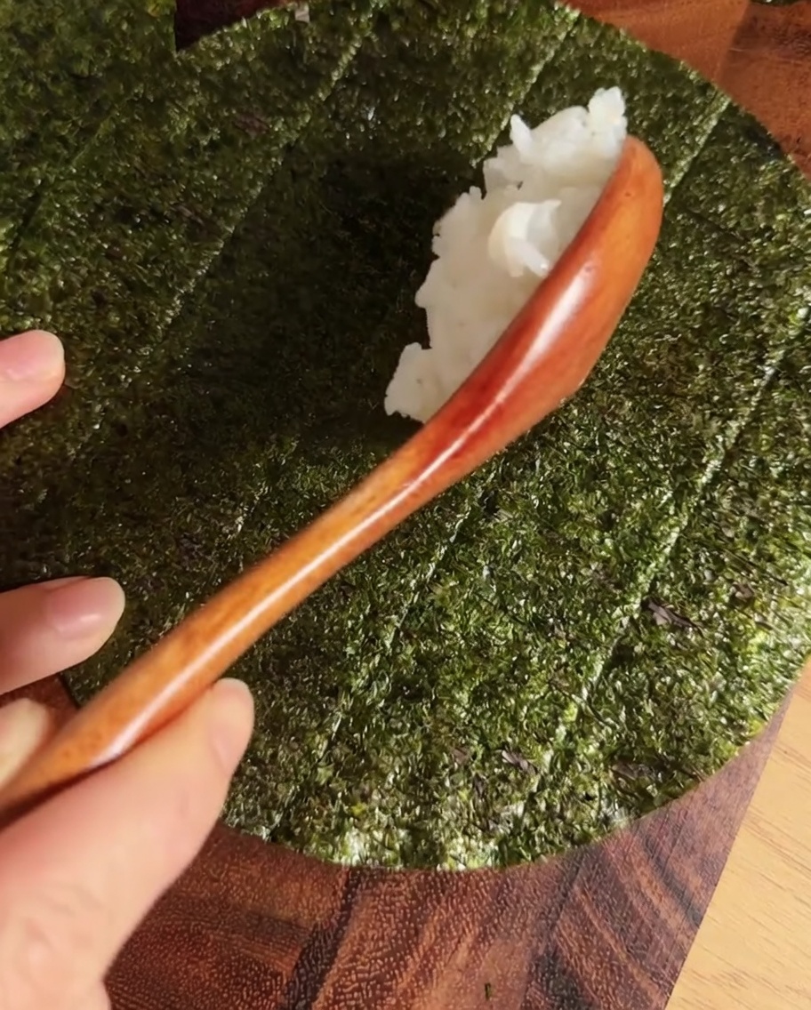 Une ligne de riz à sushis assaisonné au centre dune feuille de nori circulaire.
