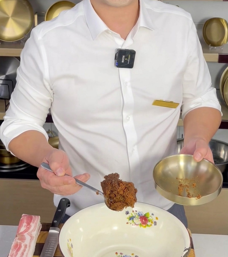 Une cuillerée de Doenjang ajoutée dans un bol à mélanger blanc, prête à être incorporée aux autres ingrédients.