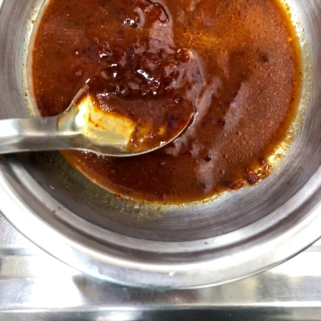 Une poudre dépices sèches saupoudrée sur le mélange de sauce préparé dans le bol en métal.