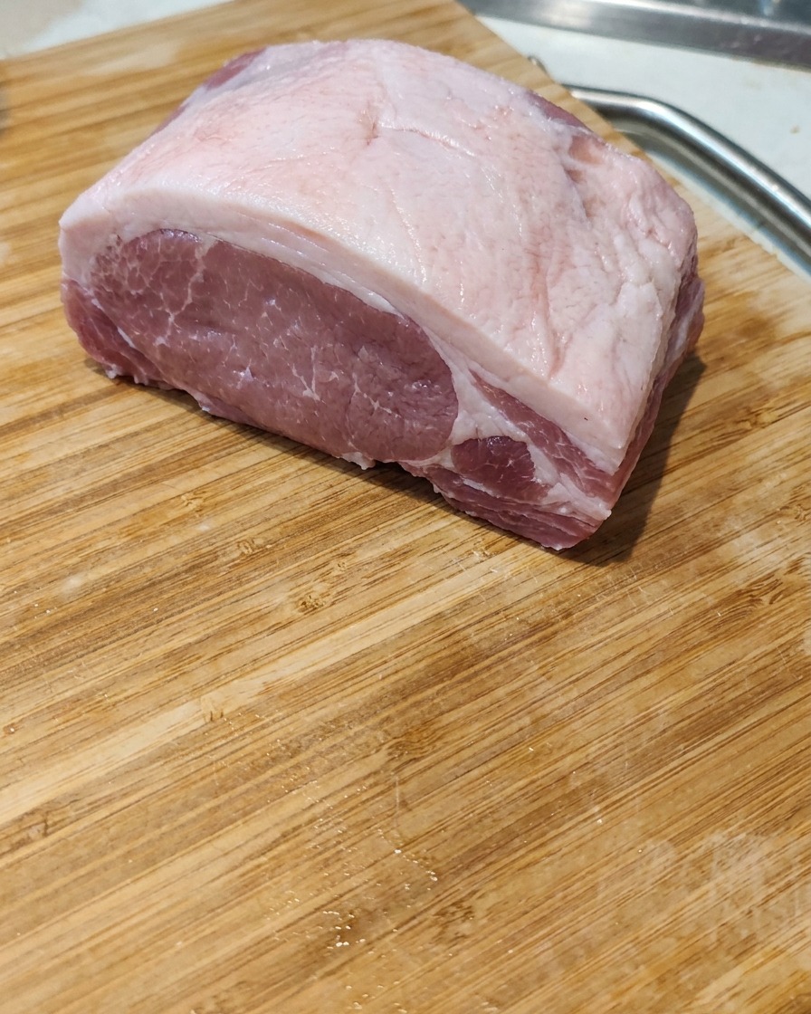 Gros plan dune tranche de poitrine de porc crue coupée en portions épaisses et égales sur une planche en bois.
