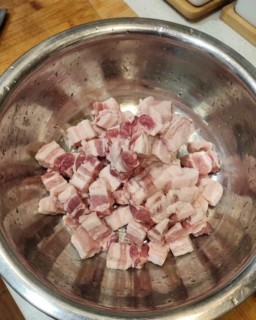 Tranches de poitrine de porc crue rassemblées dans un grand bol en acier inoxydable.