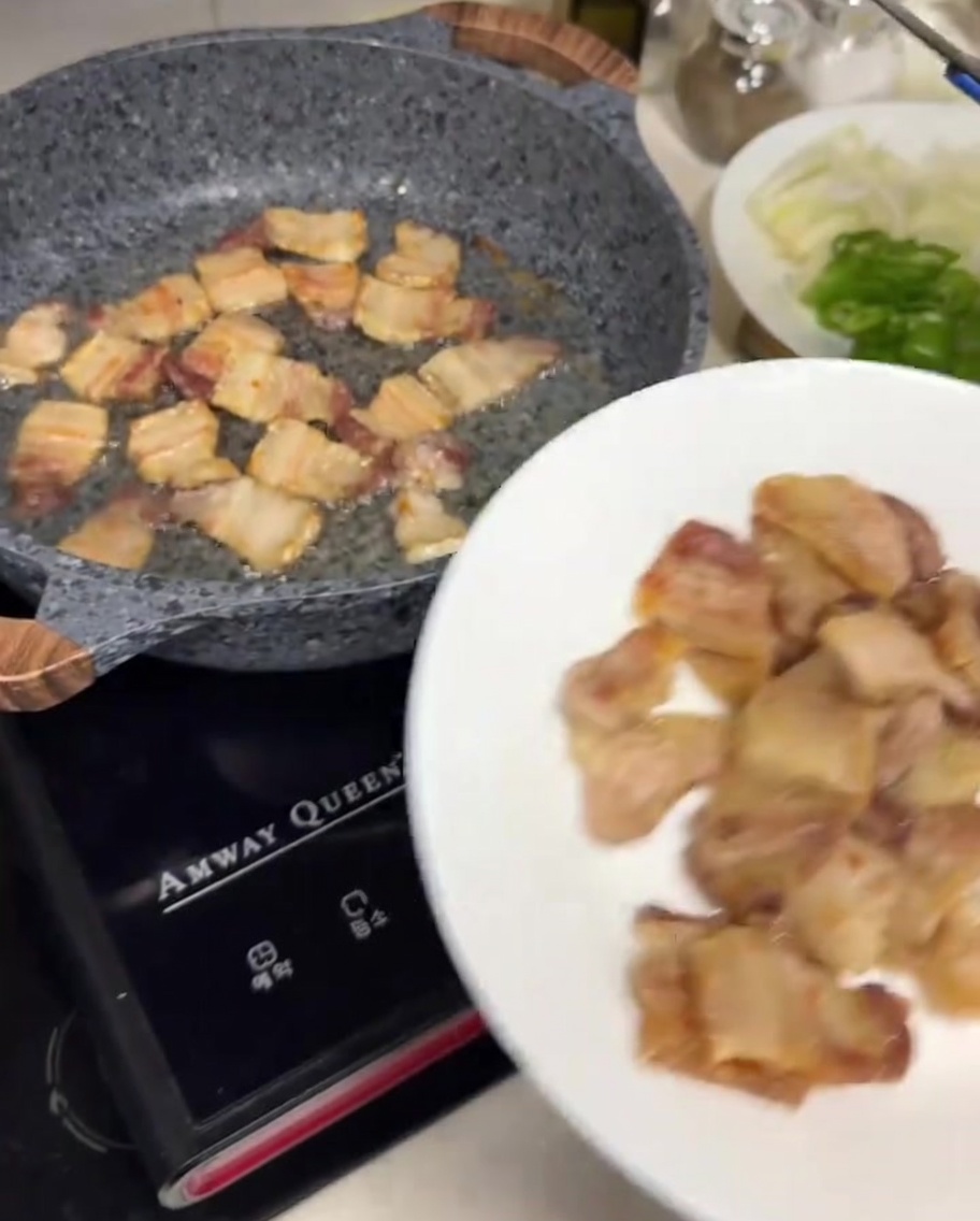Pinces en métal déposant des tranches de porc croustillantes sur une assiette blanche.
