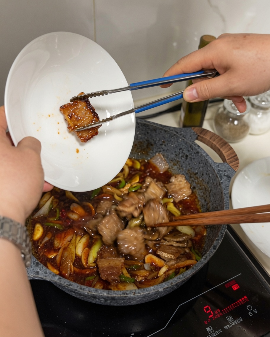 Tranches de poitrine de porc ajoutées depuis une assiette dans un wok rempli de sauce frémissante et de légumes.