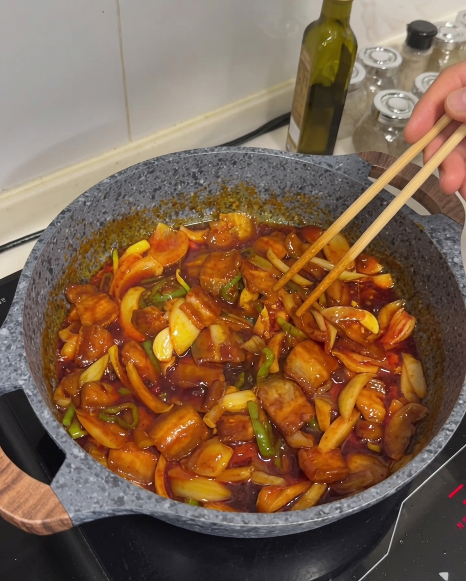 Sauté de poitrine de porc épicé fini dans une poêle et garni de graines de sésame.