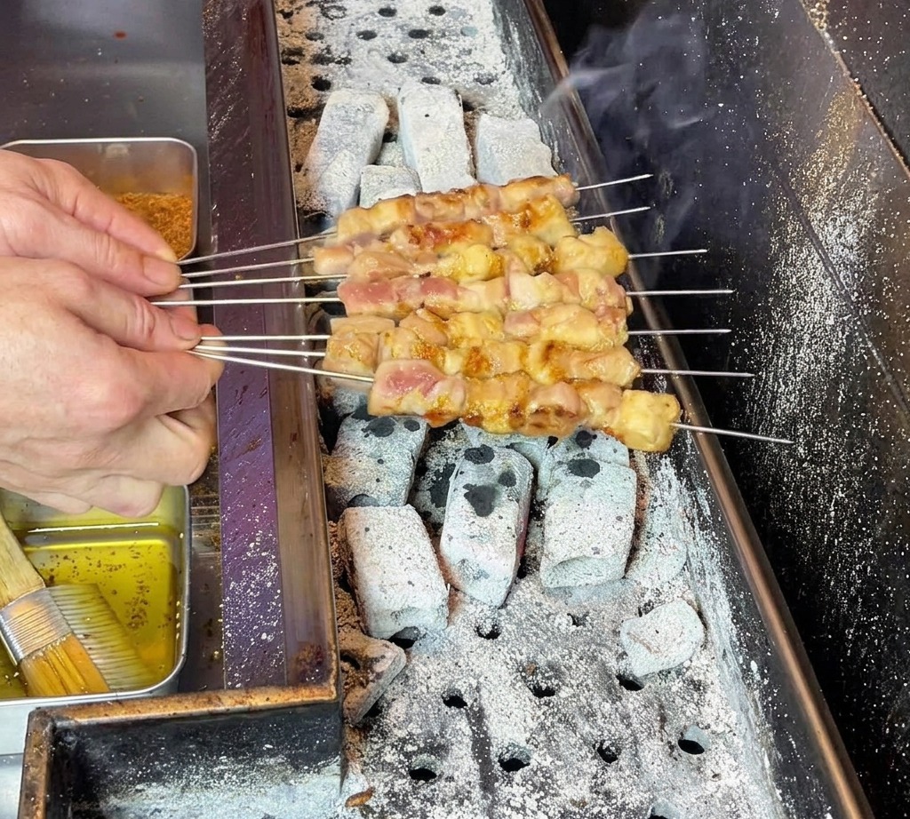 Les mains du chef manipulant soigneusement les brochettes pour répartir la graisse sur la viande.