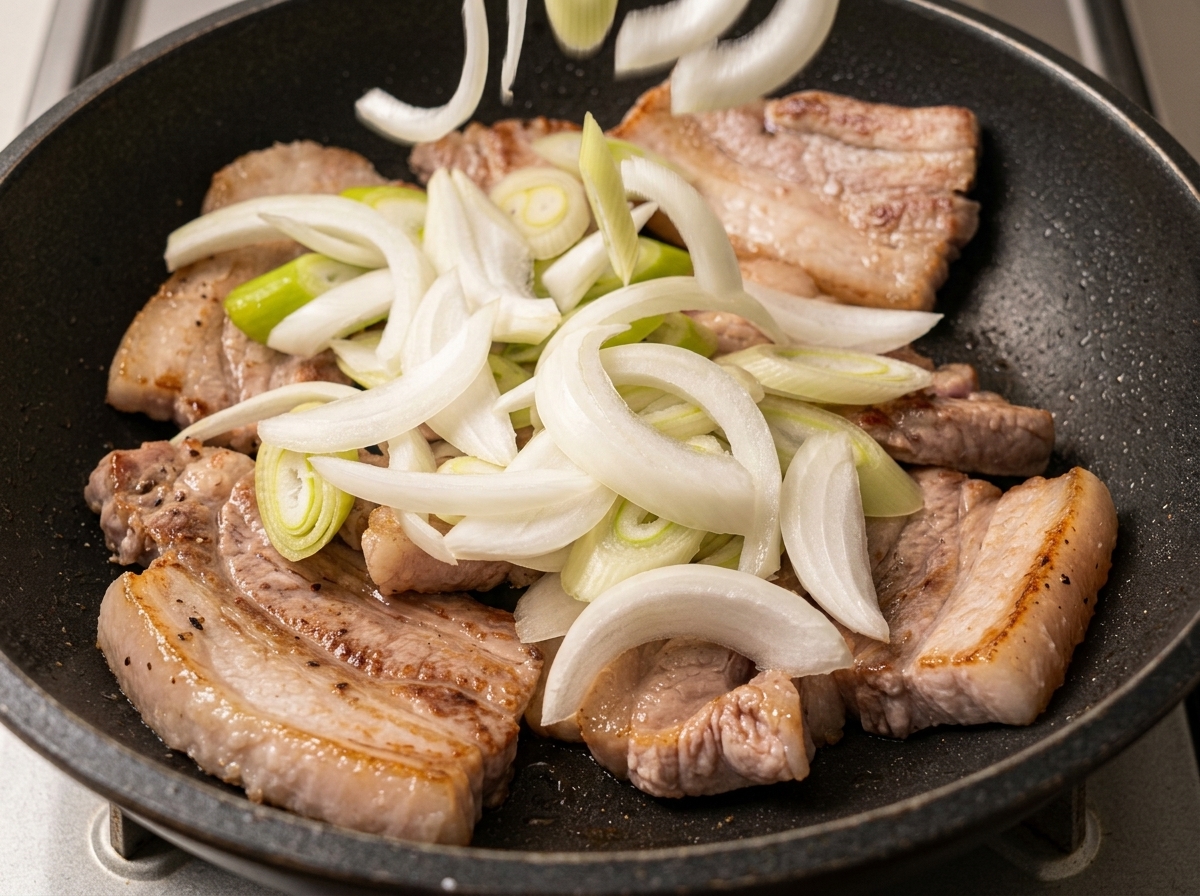 Oignons blancs et oignons verts émincés dispersés sur les tranches de porc dorées.