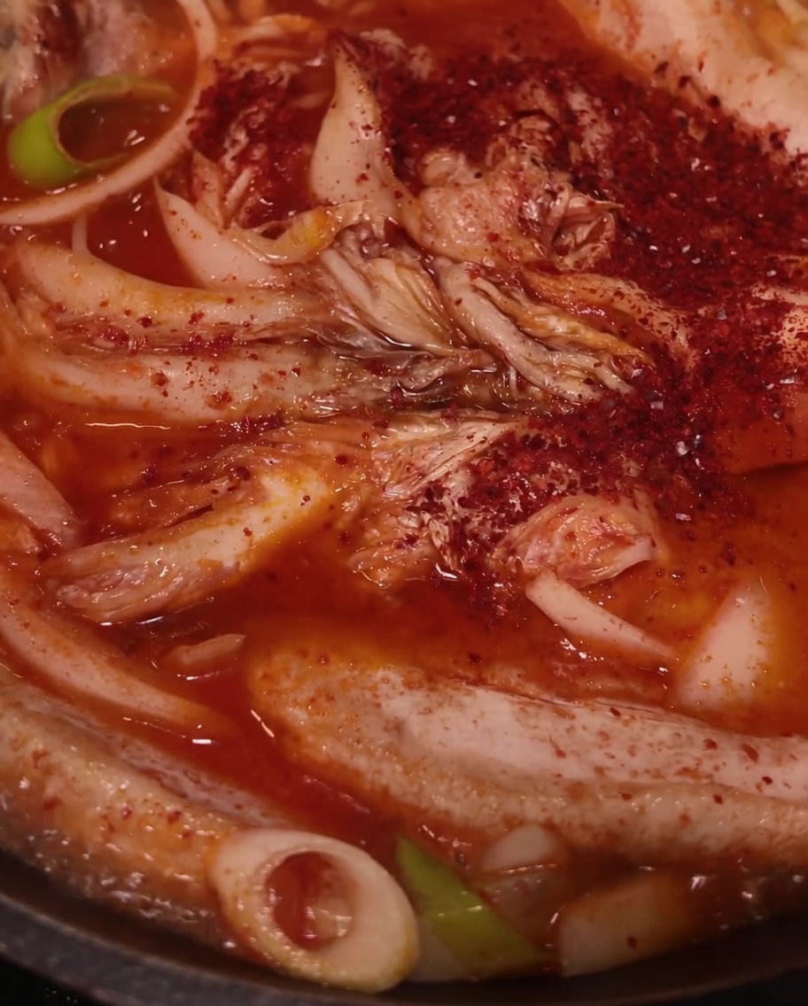 Poudre de piment rouge saupoudrée sur le porc, le kimchi et les oignons.