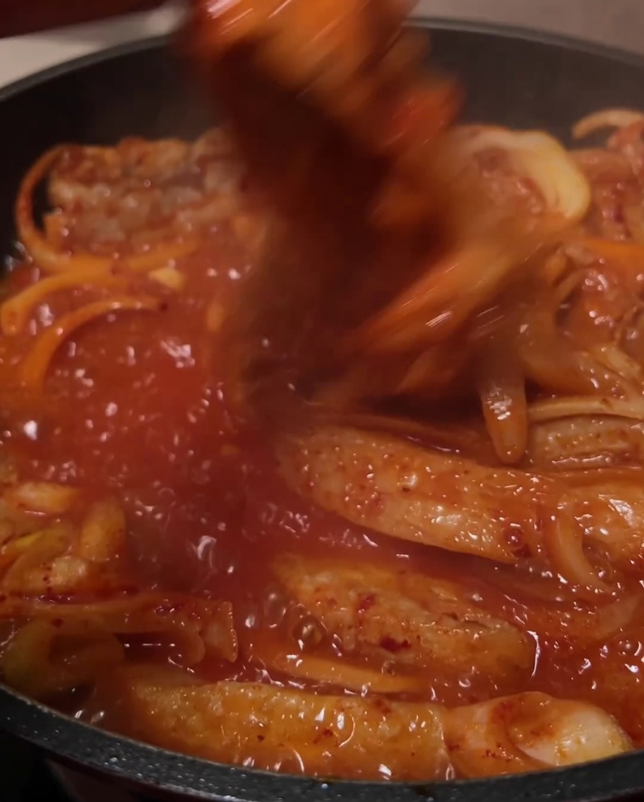 Les ingrédients mélangés dans la sauce rouge bouillonnante.