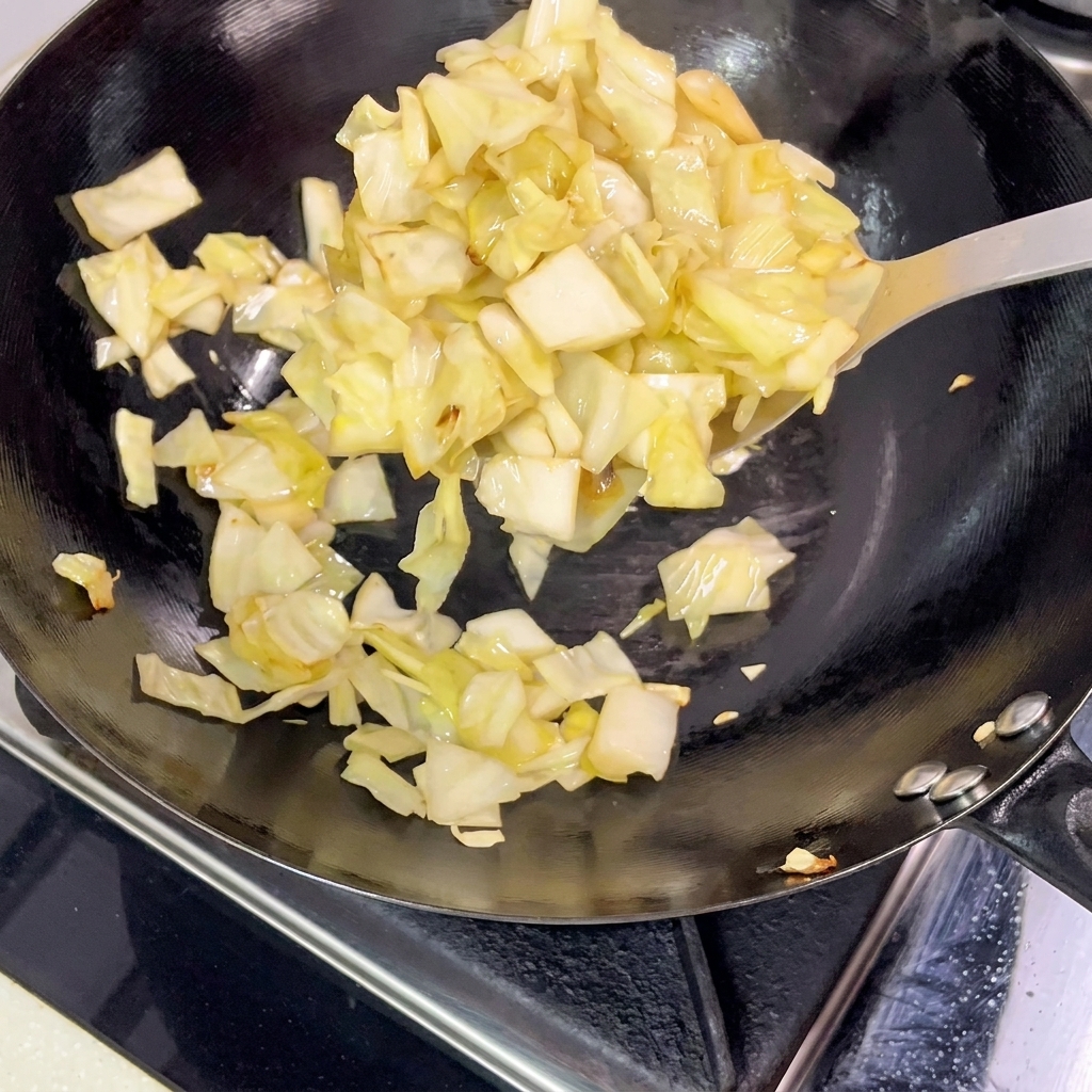 Morceaux de chou mariné retirés dun wok très chaud à laide dune spatule en métal.