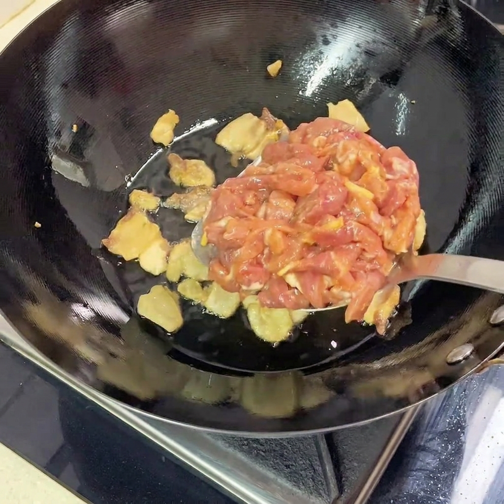 Lanières de porc maigre marinées ajoutées dans le wok chaud avec la poitrine de porc rissolée.