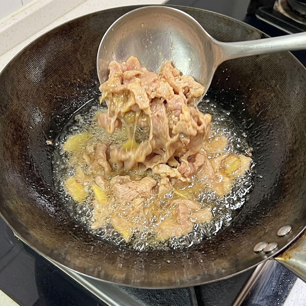 Tranches de porc cuisant dans le wok, montrant une surface bien dorée et caramélisée.