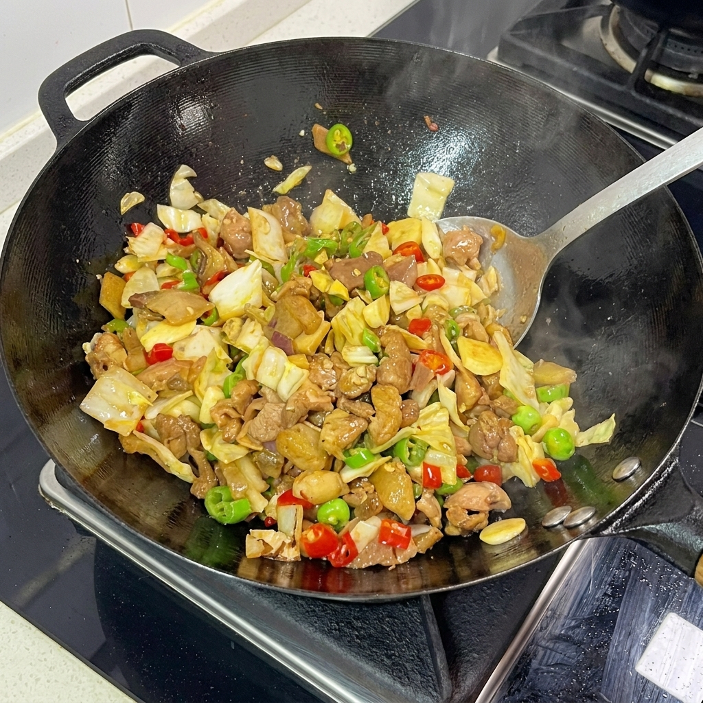 Spatule mélangeant vigoureusement le chou mariné, les tranches de porc et les piments dans un wok fumant.