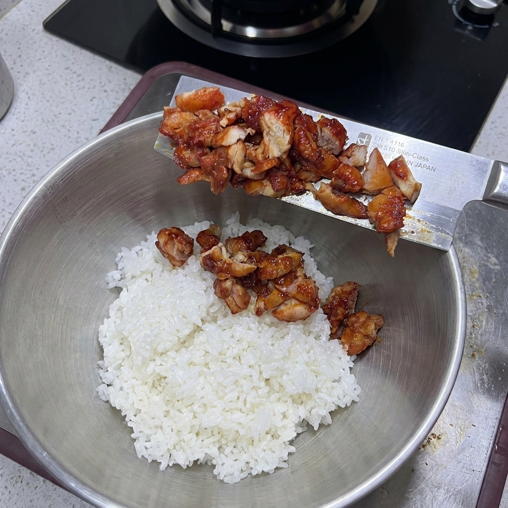 Poulet cuit coupé glissé dans un grand bol rempli de riz blanc moelleux.