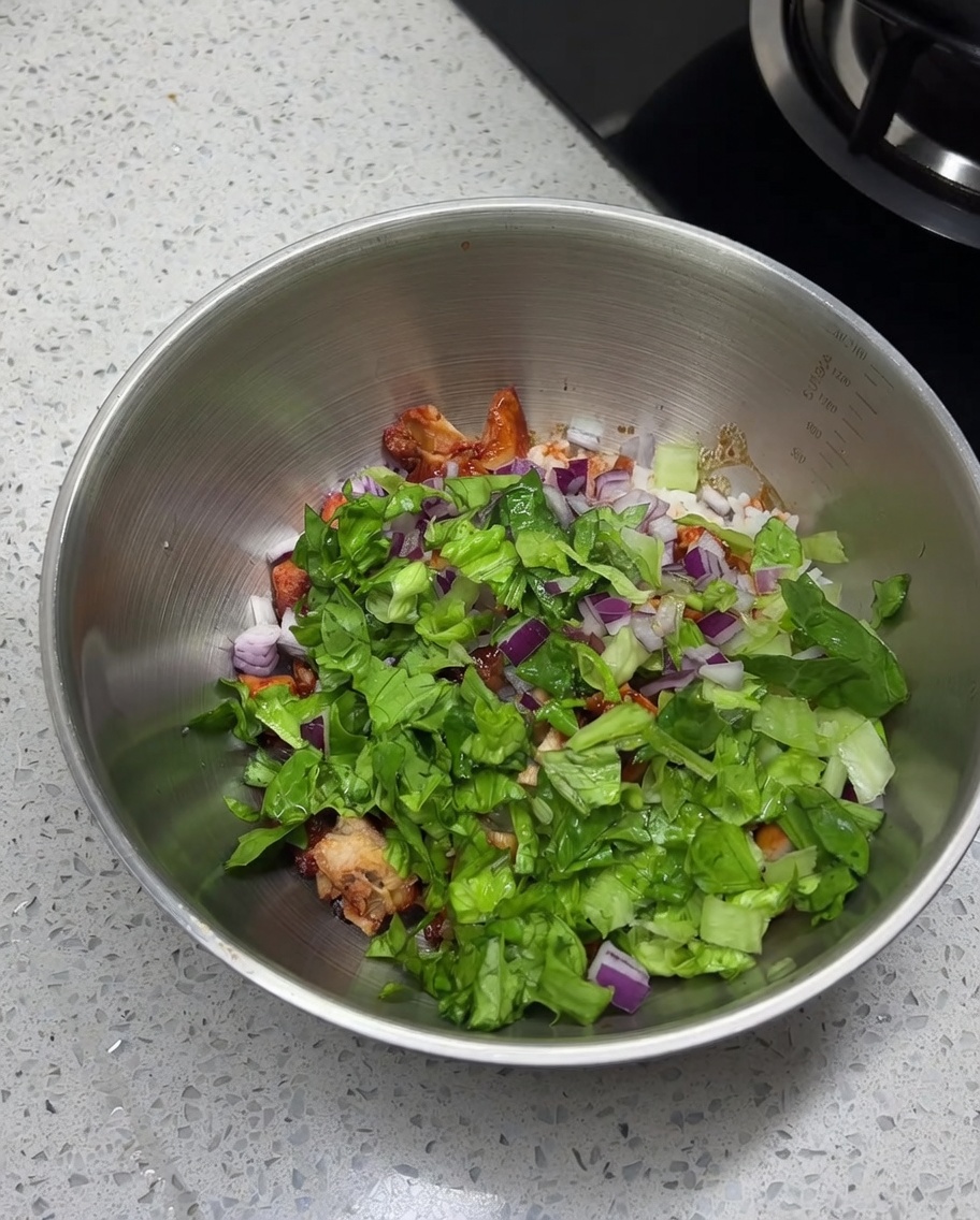 Gros plan sur du sel, du cumin en poudre et du piment en poudre saupoudrés sur le mélange de poulet, de riz et de légumes.