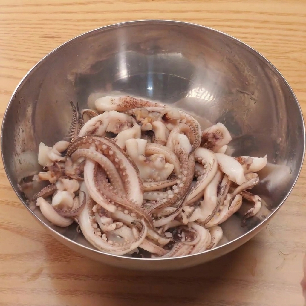 Tentacules de calamar frais immergés dans un bol deau bouillante pour un blanchiment rapide.