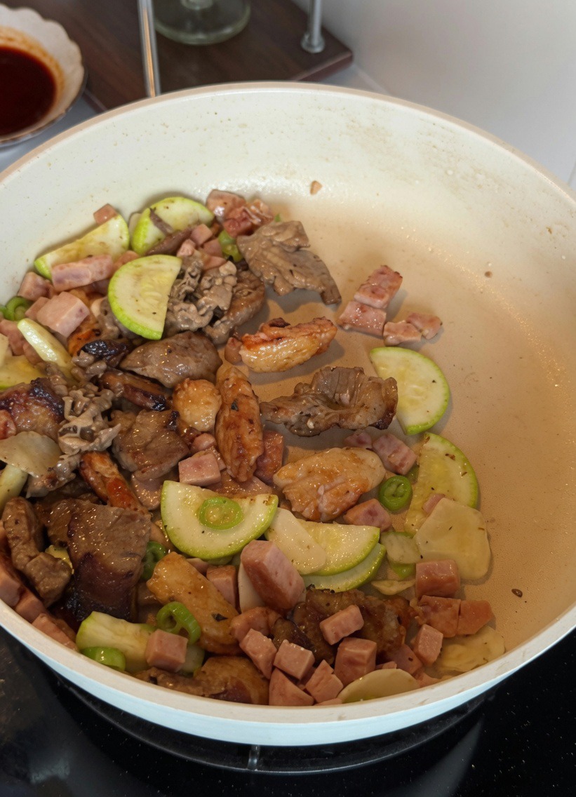 Mélange dœufs battus brouillé avec des courgettes et de la viande dans une poêle blanche.