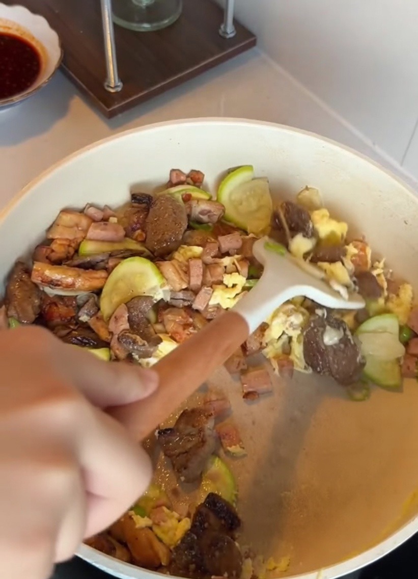 Un bol de riz blanc ajouté à une poêle contenant des courgettes, de la viande et des œufs sautés.
