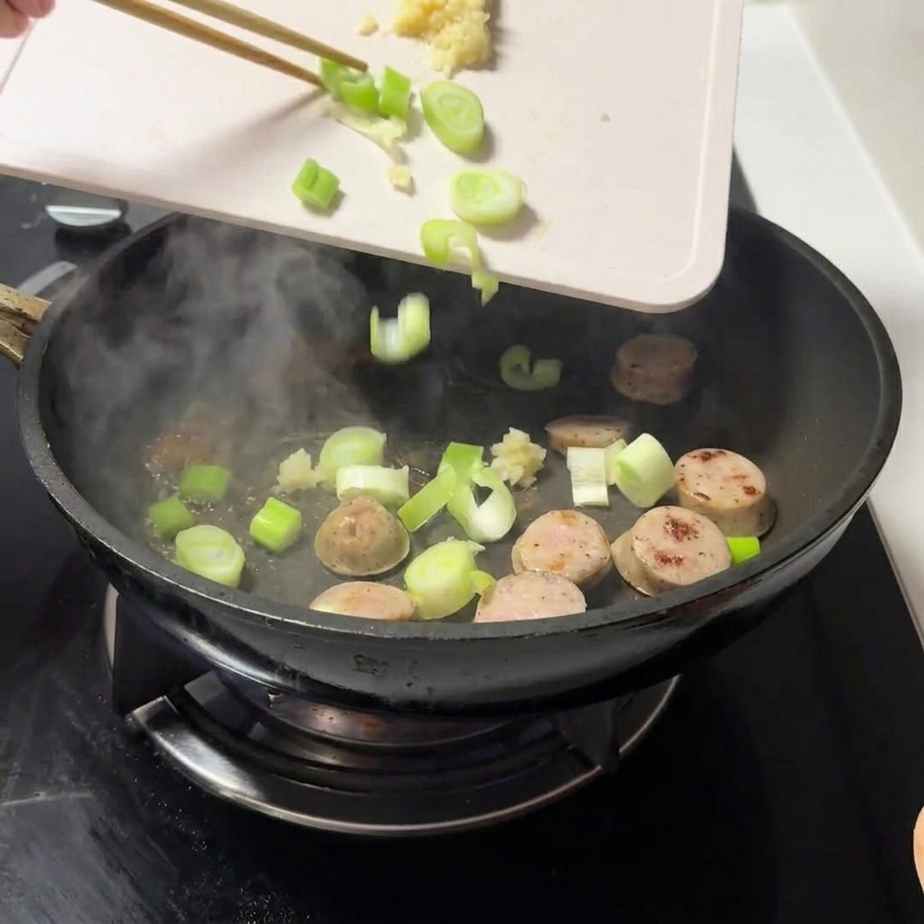 Oignons verts hachés et ail émincé ajoutés dans la poêle avec la viande.
