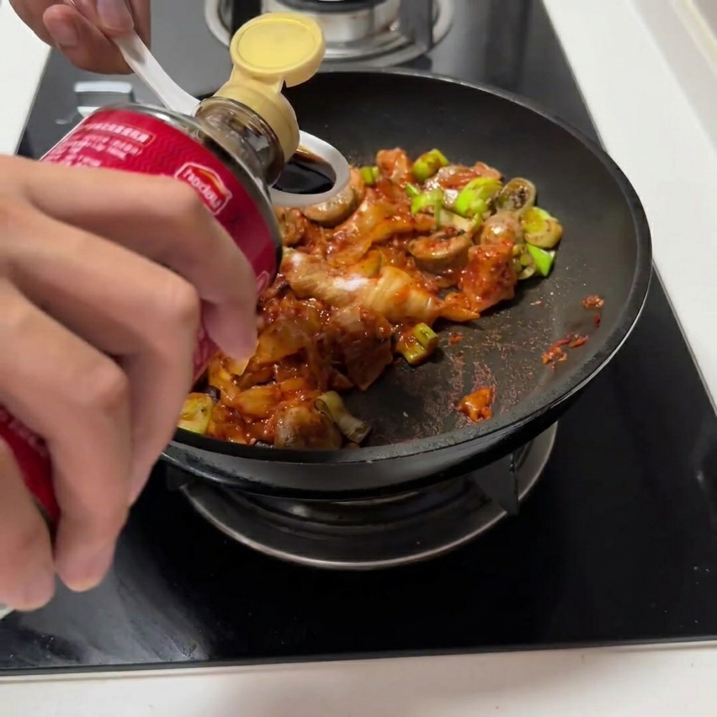 La sauce soja et la sauce huître versées dans la poêle avec le mélange de kimchi.